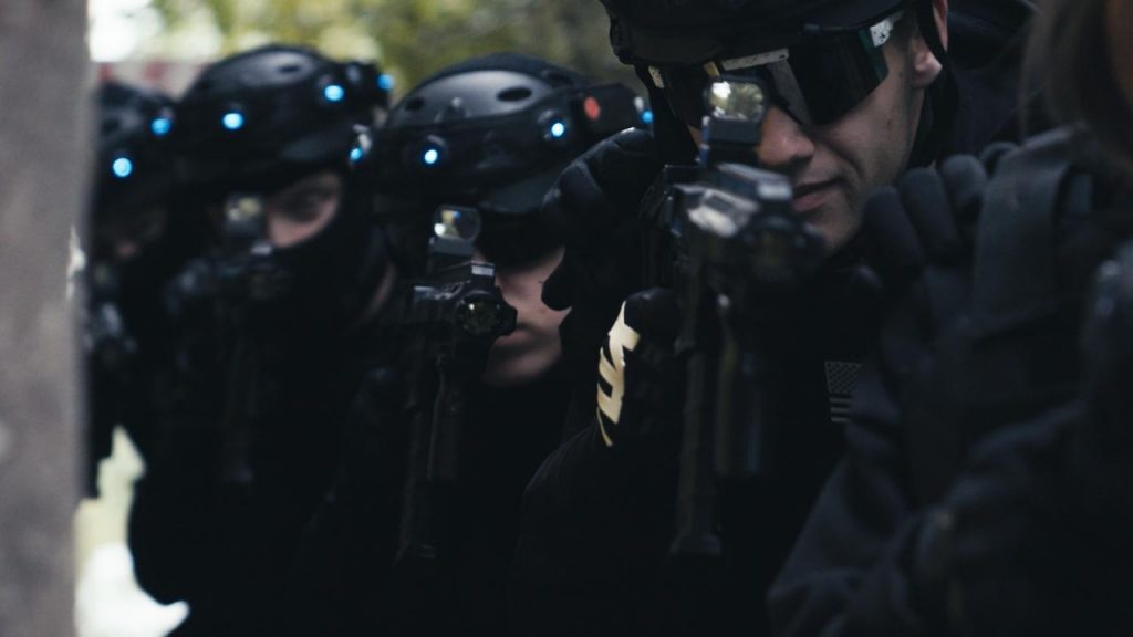 Nahaufnahme mehrerer SWAT-Agenten in schwarzer Ausrüstung in der Outdoor-Lasertag-Arena Wels, bewaffnet und in Reihe hintereinander. Szene aus dem Projekt "The Extraction" von XENTRA FILMS.