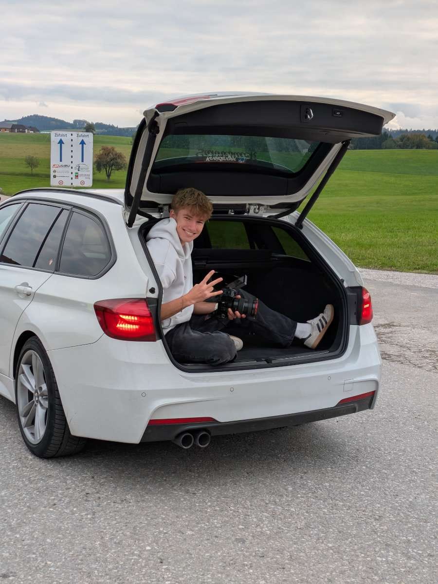 Jannis Danner im Kofferaum eines weißen BMW's beim Roller-Shots-Filmen