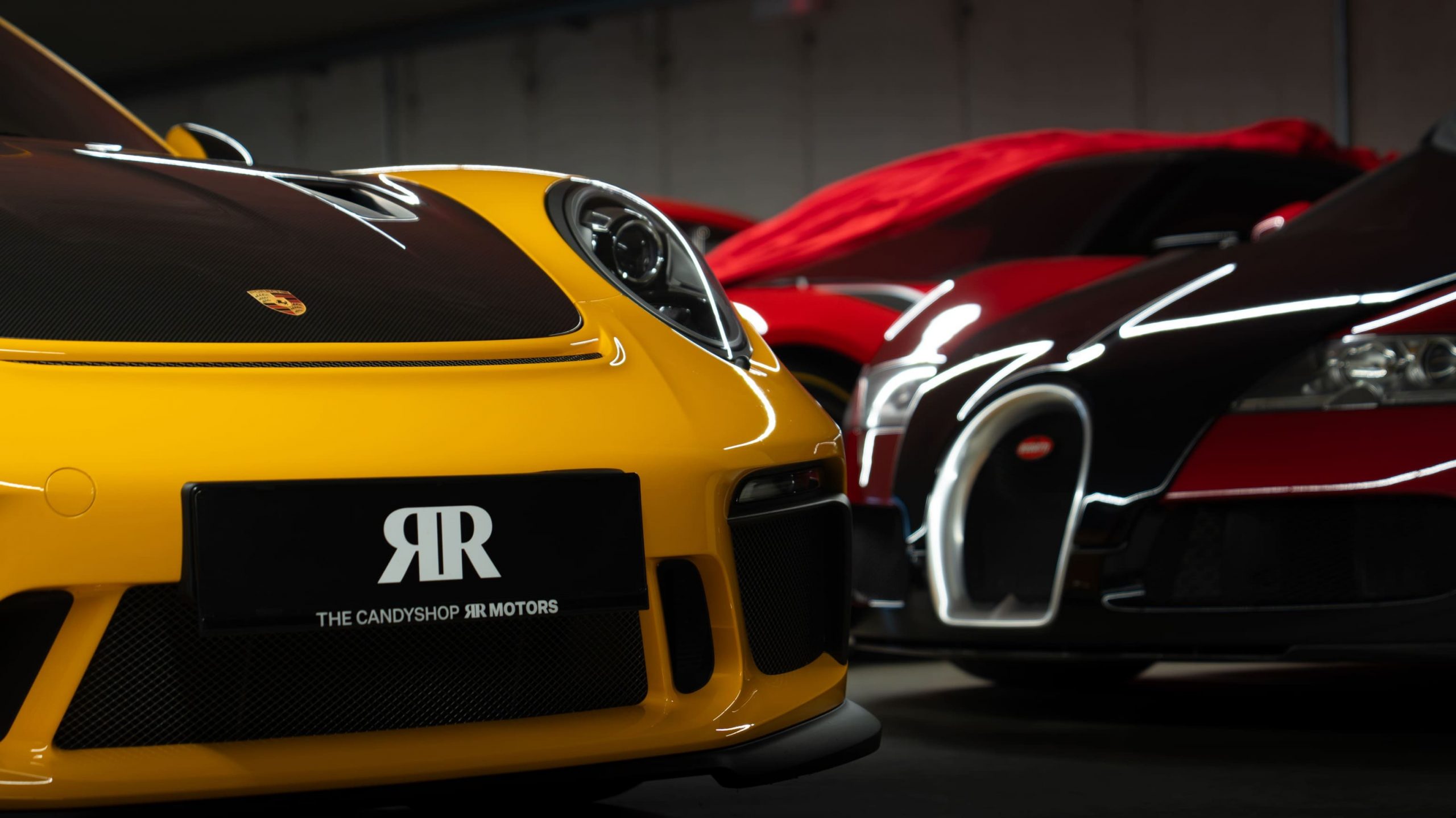 Gelber Porsche im Vordergrund und Bugatti Veyron.