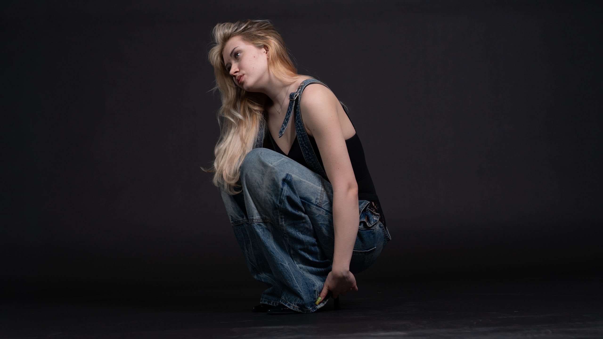 Model Naemi Krösche in einer Latzhose vor schwarzem Hintergrund im Fotostudio