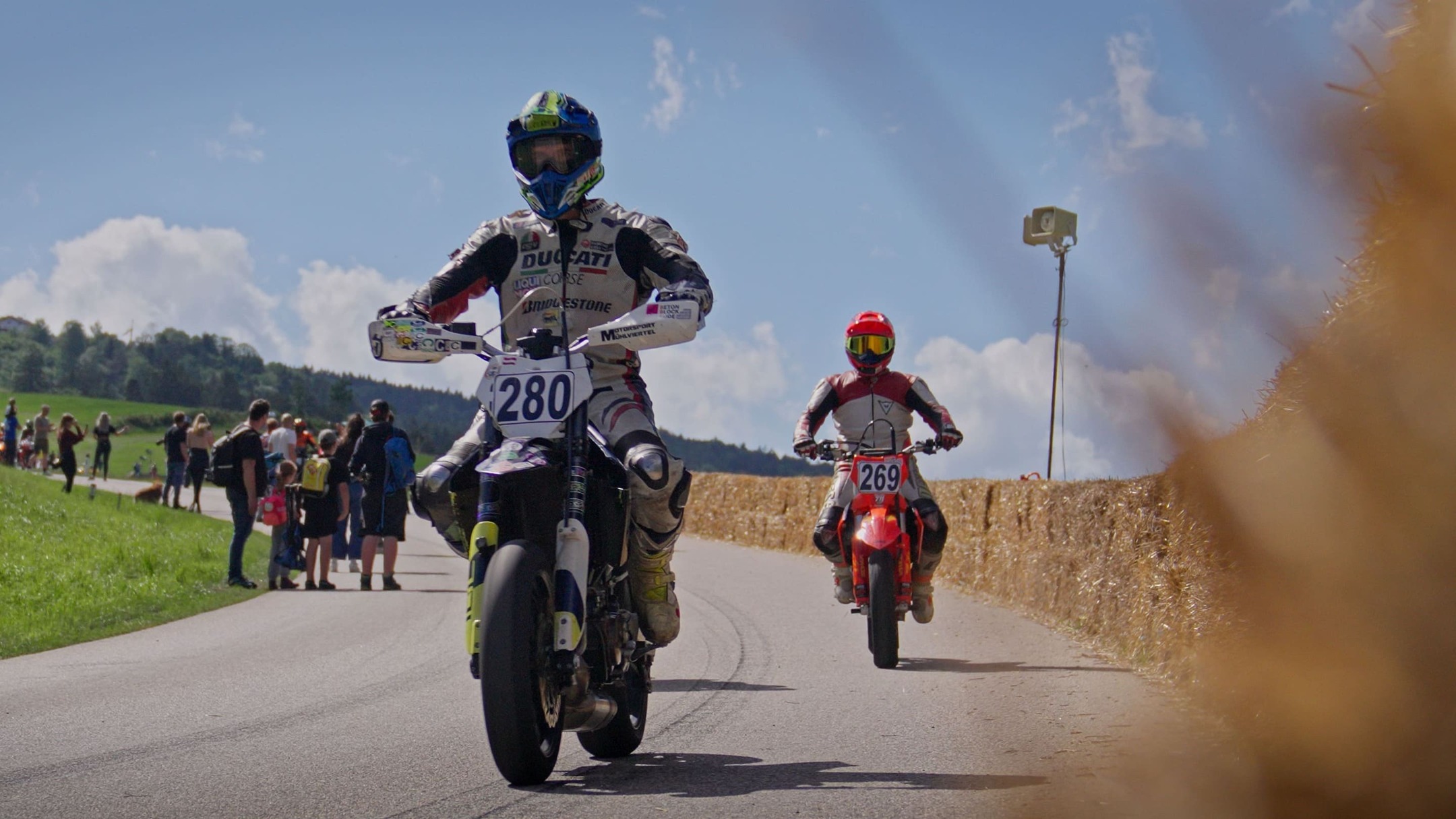 Supermoto Fahrer im Stehen bei der Rückführung, im Vordergrund ein Strohballen, Julbach Bergrennen