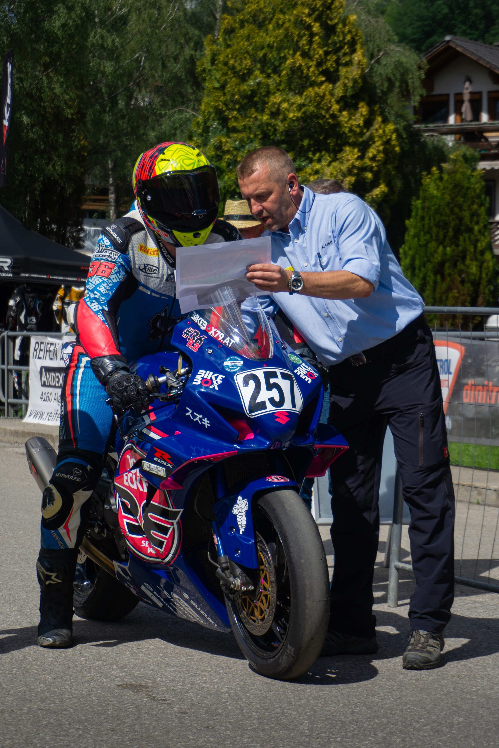 Fahrer auf blauem Superbike mit Startnummer 45 im Gespräch mit einem Streckenposten am Start in Julbach