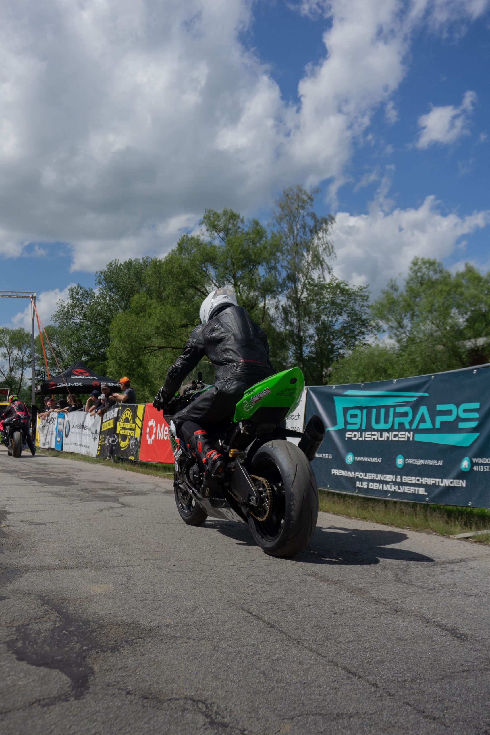 Grüne Kawasaki beim Start des Motorrad Bergrennens Julbach 2026, dahinter Zuschauer und Werbebanner