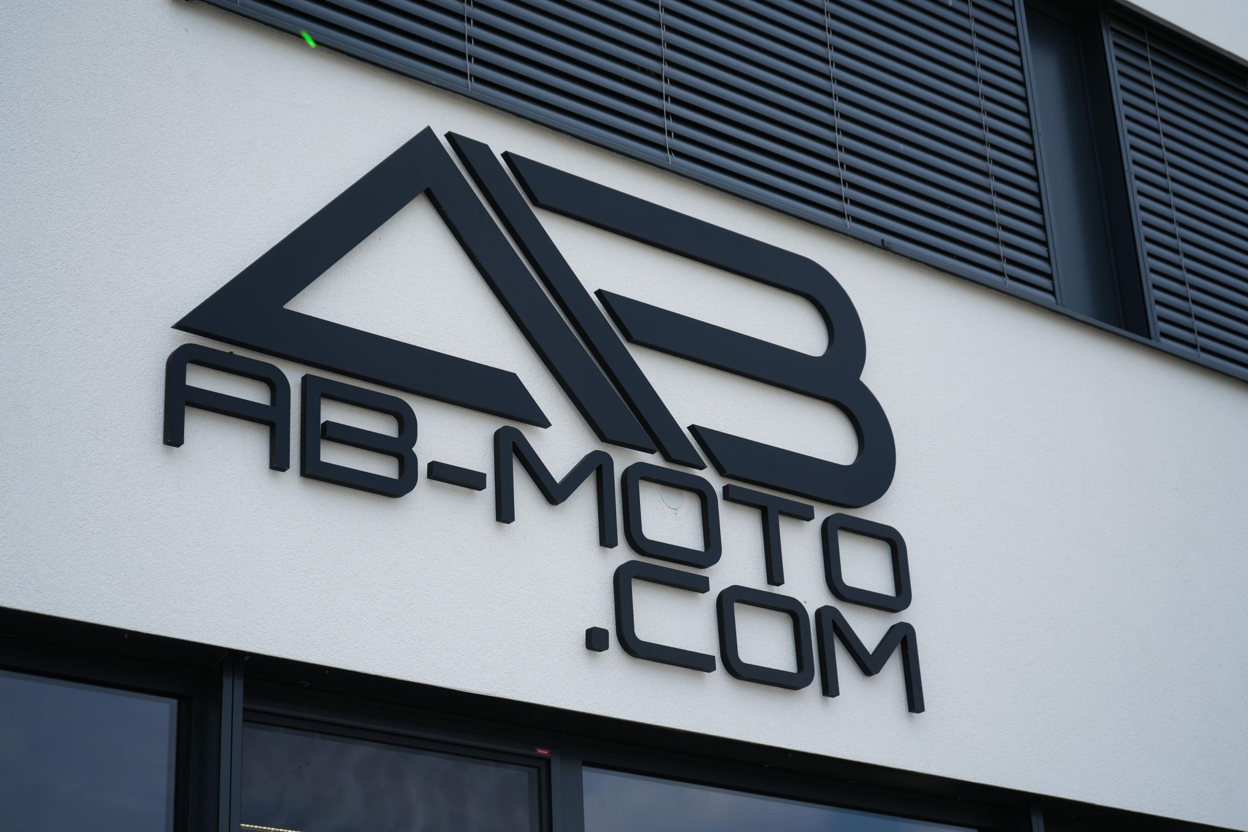 Logo von AB-Moto mit Webadresse an der Fassade des Stores in Lungitz