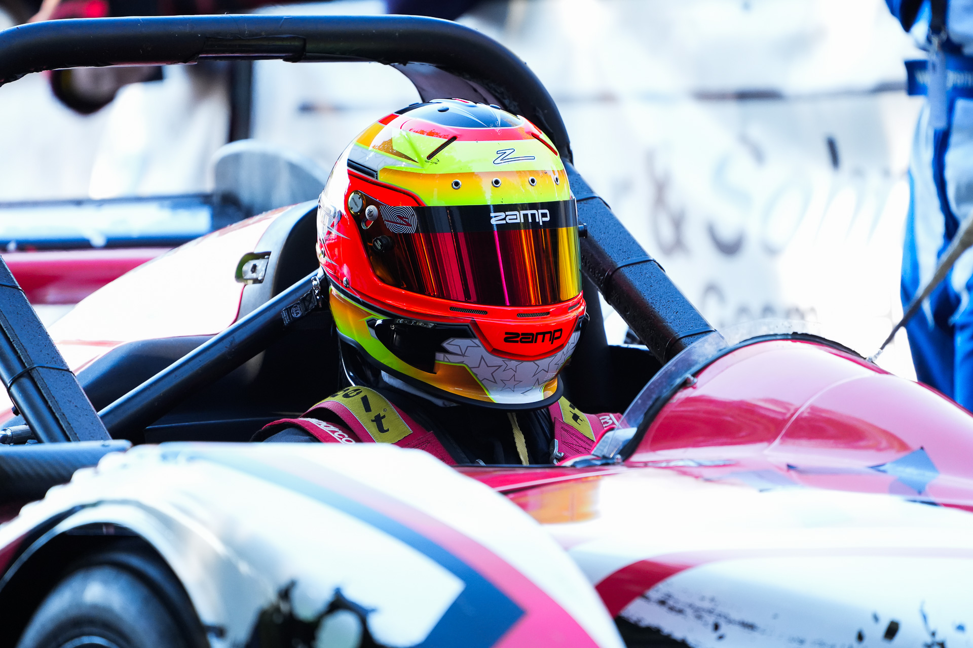 Fahrer mit pink rotem Helm sitzt im Cockpit des pink lackierten Proto Fahrzeugs