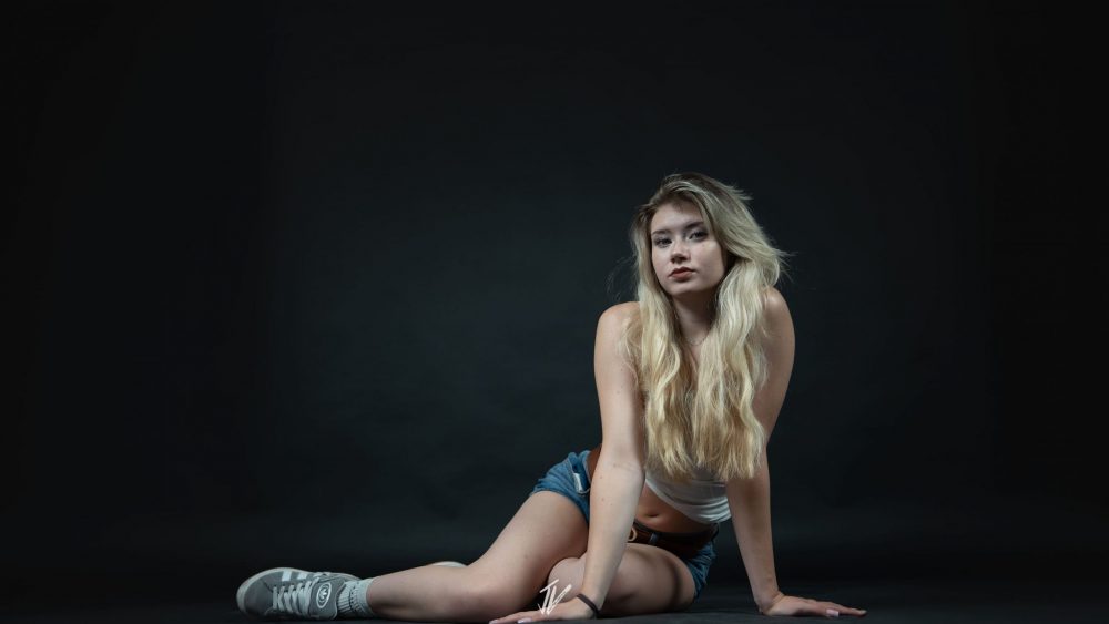 Naemi Krösche in sitzender Pose vor schwarzem Hintergrund.