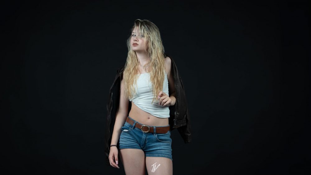 Naemi Krösche steht im weißen Top vor dunklem Hintergrund.