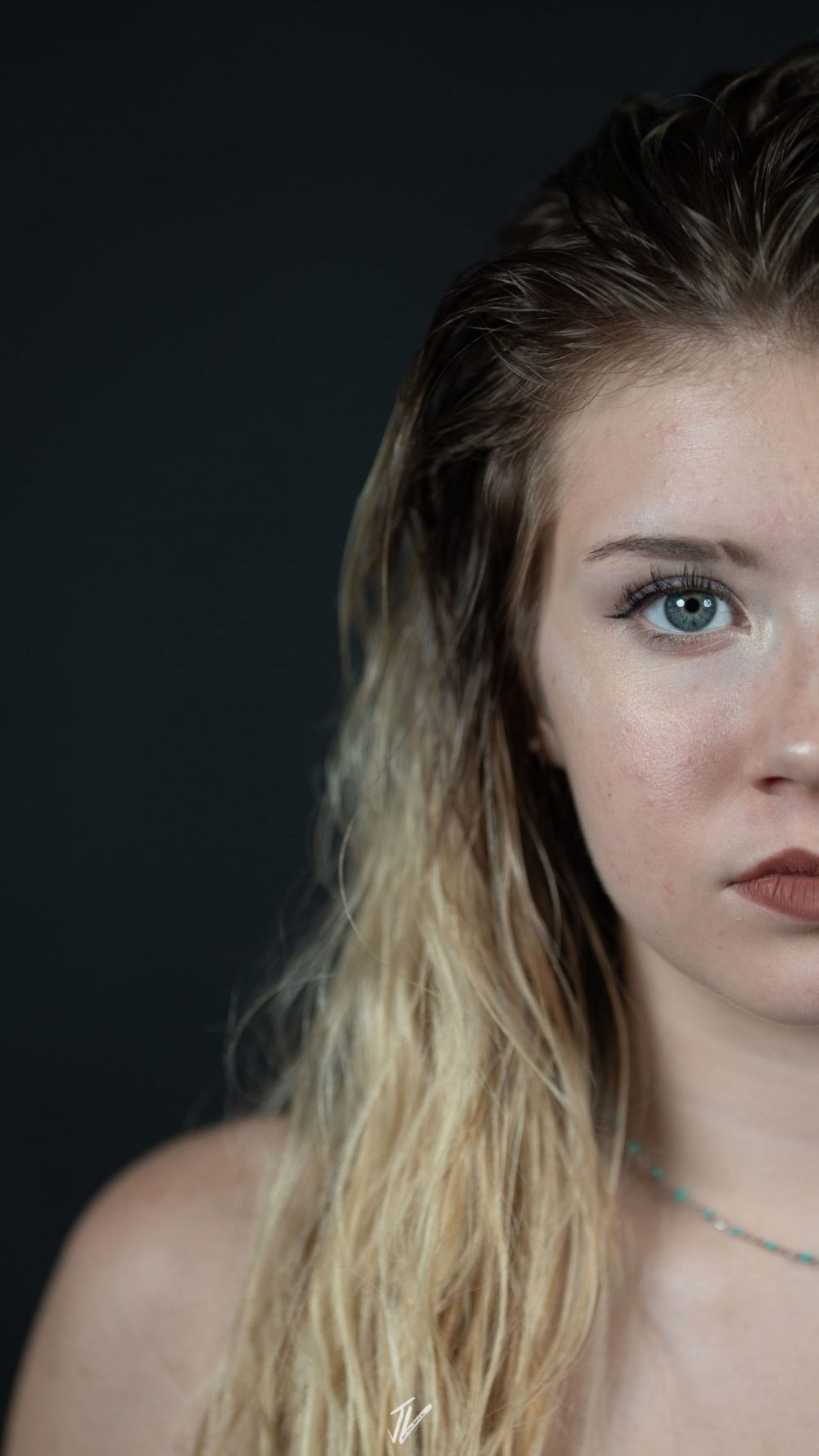 Natürliches Porträt von Naemi Krösche im dunklen Fotostudio.