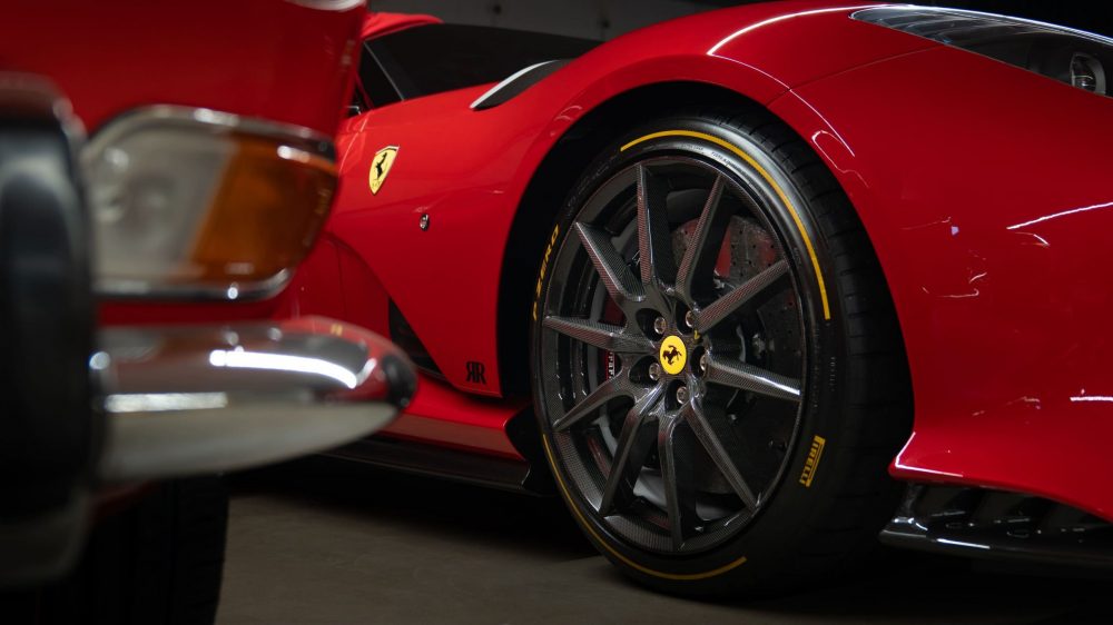 RR Motors Candy Shop Autohaus 14 Carbon Felge eines roten Ferraris in einer großen Garage.