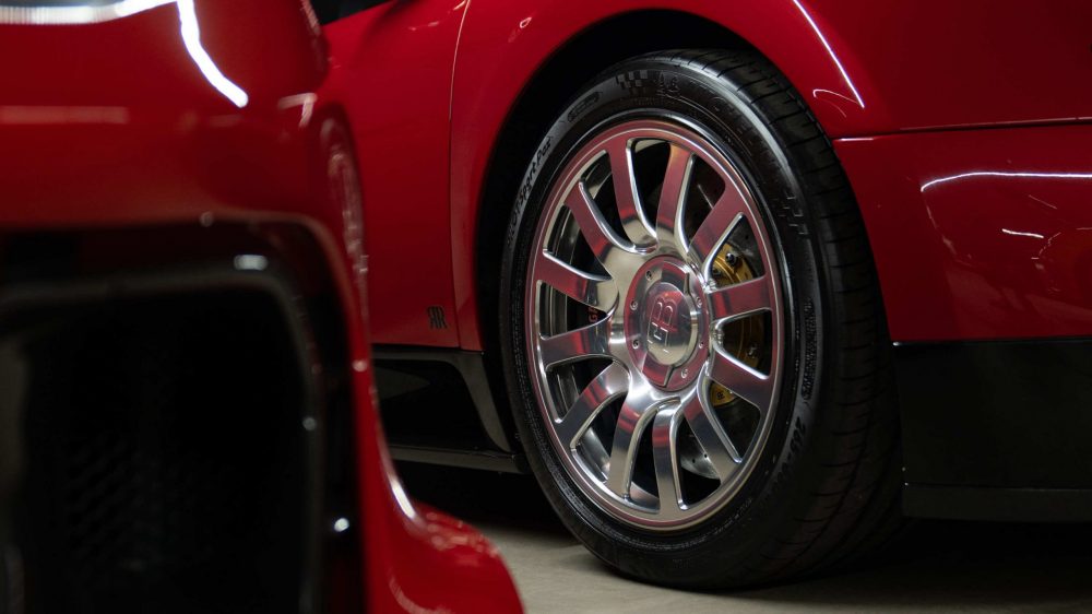 RR Motors Candy Shop Autohaus 22 Chrome Felge eines roten Bugatti Veyrons in einer großen Garage.