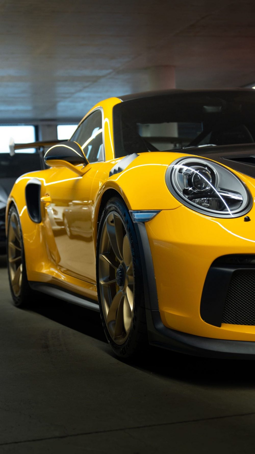 RR Motors Candy Shop Autohaus 27 Gelber Porsche mir goldenen Felgen in einer großen Garage.