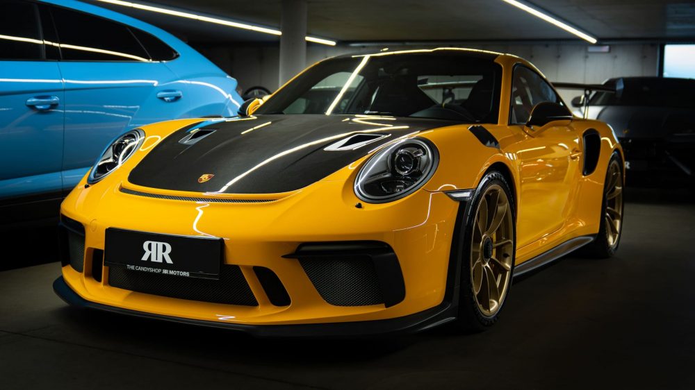 RR Motors Candy Shop Autohaus 23 Gelber Porsche GT3 in einer großen Garage.