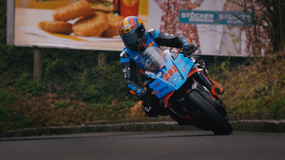 Landshaag Bergrennen 2026 | Oberösterreich Superbike in Blau und Orange in Schräglage vor Plakatwand beim Landshaag Bergrennen 2026
