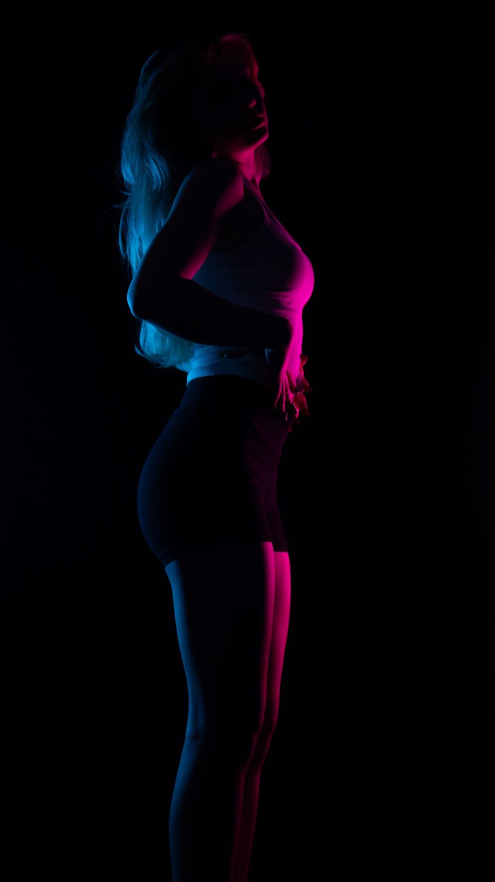 Naemi Krösche Model Shooting | HTL Paul Hahn, Linz Naemi Krösche steht seitlich im dunklen Studio mit pinkem Kantenlicht