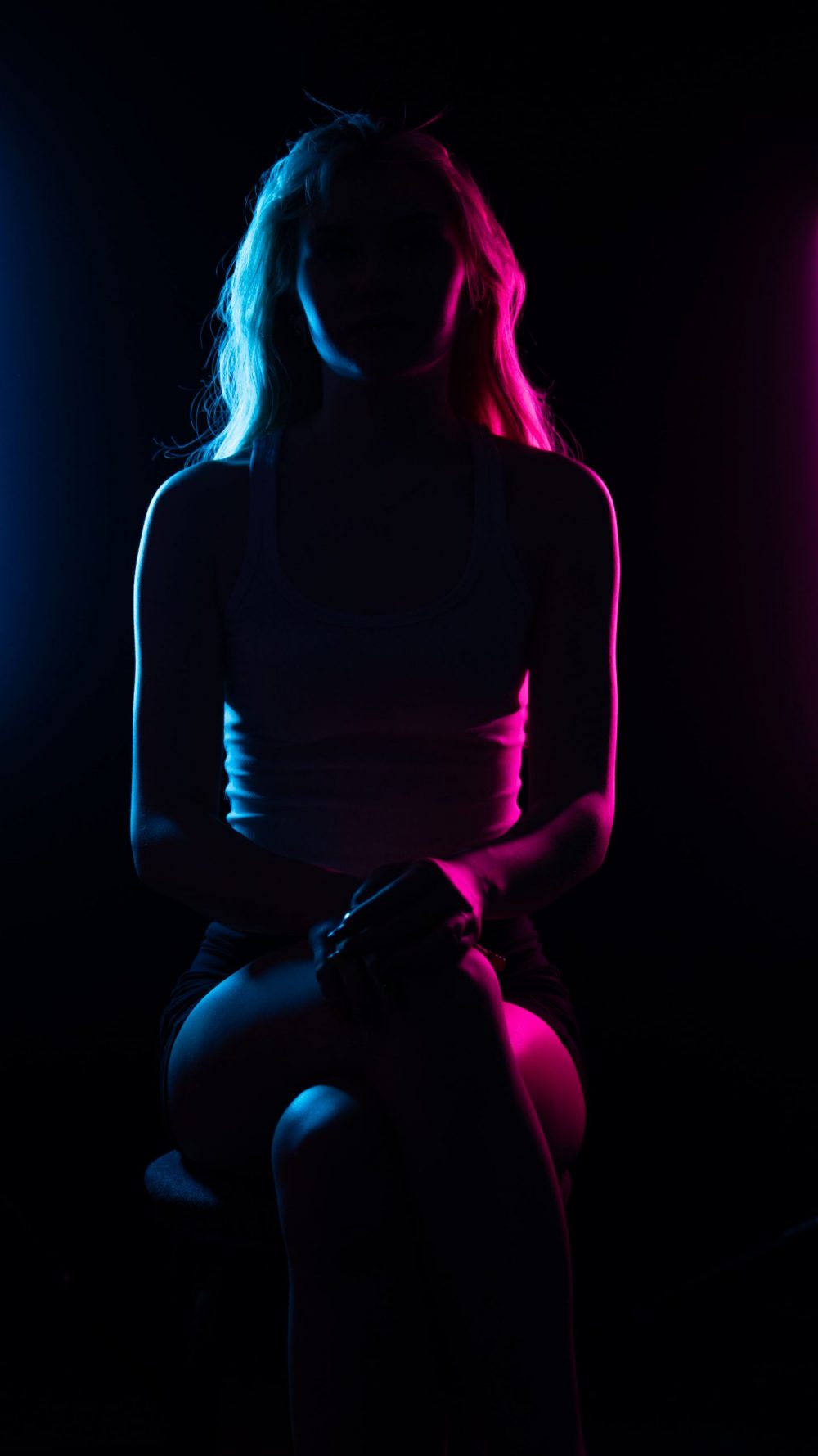 Naemi Krösche Model Shooting | HTL Paul Hahn, Linz Naemi Krösche sitzt frontal als Silhouette mit farbigem Kantenlicht im Studio