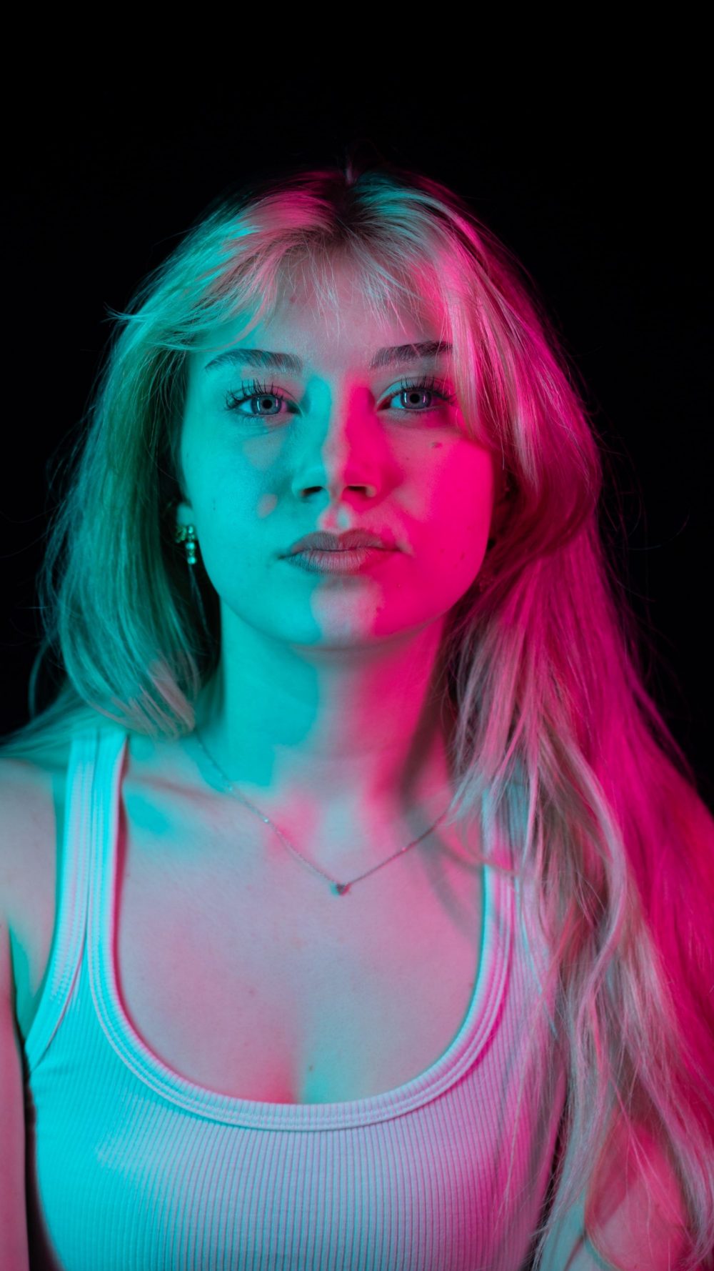 Naemi Krösche Model Shooting | HTL Paul Hahn, Linz Nahes Porträt von Naemi Krösche mit türkisem und pinkem Licht im Gesicht