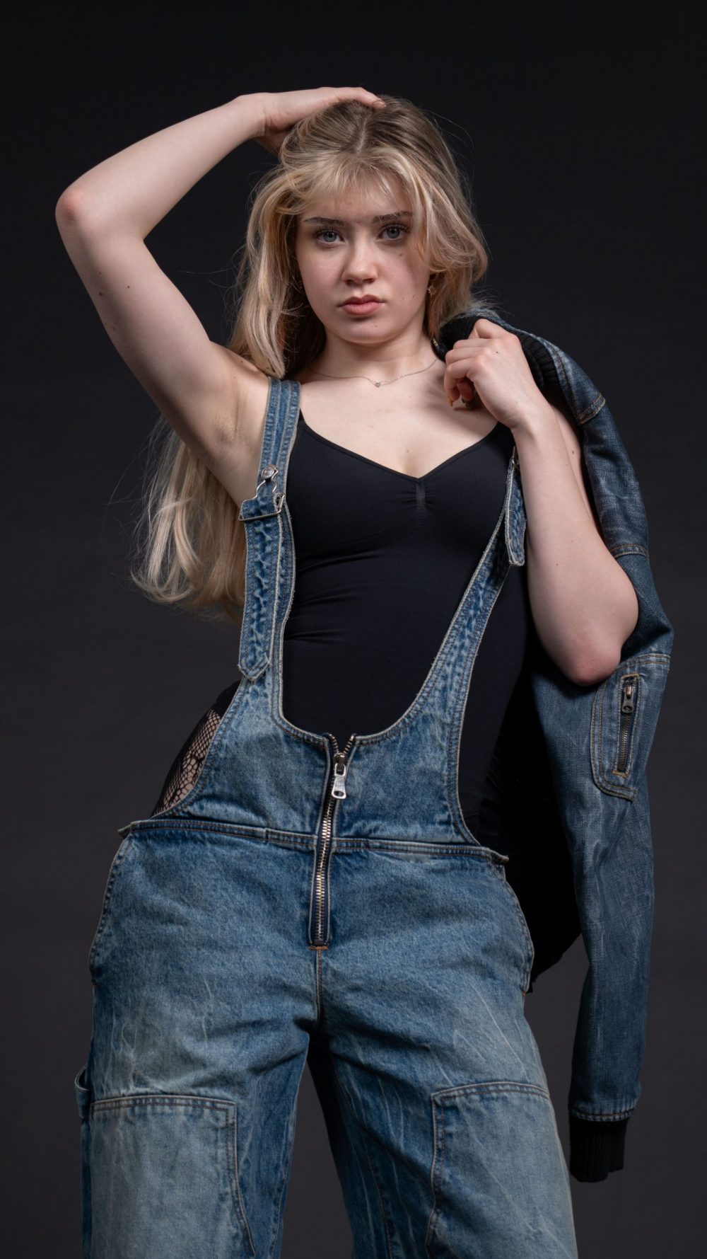 Naemi Krösche Model Shooting | HTL Paul Hahn, Linz Naemi Krösche in Latzhose mit Jeansjacke über der Schulter und Hand im Haar
