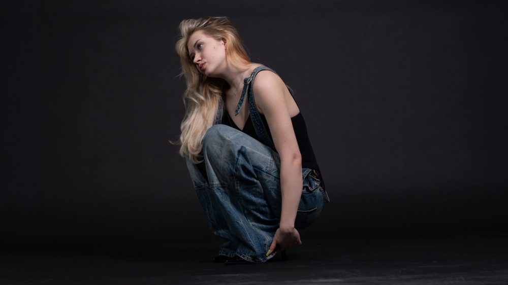 Naemi Krösche Model Shooting | HTL Paul Hahn, Linz Model Naemi Krösche in einer Latzhose vor schwarzem Hintergrund im Fotostudio