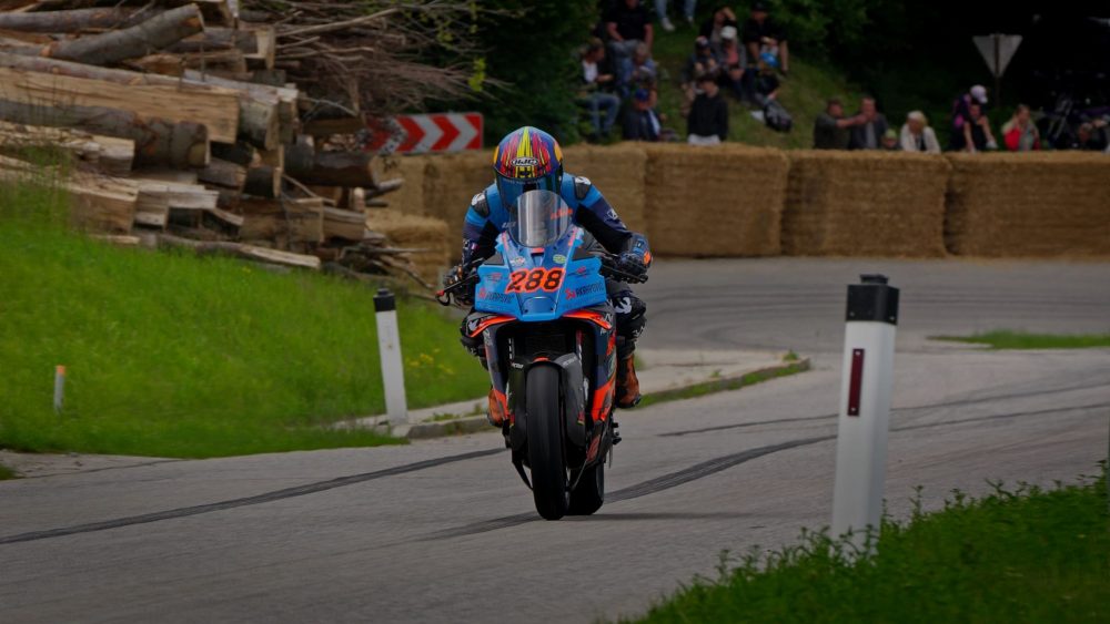 Bergrennen Julbach 2026 | Julbach, Oberösterreich Fahrer auf blauem Superbike kommt an Holzstapeln vorbei aus der Kurve beim Motorradrennen in Julbach