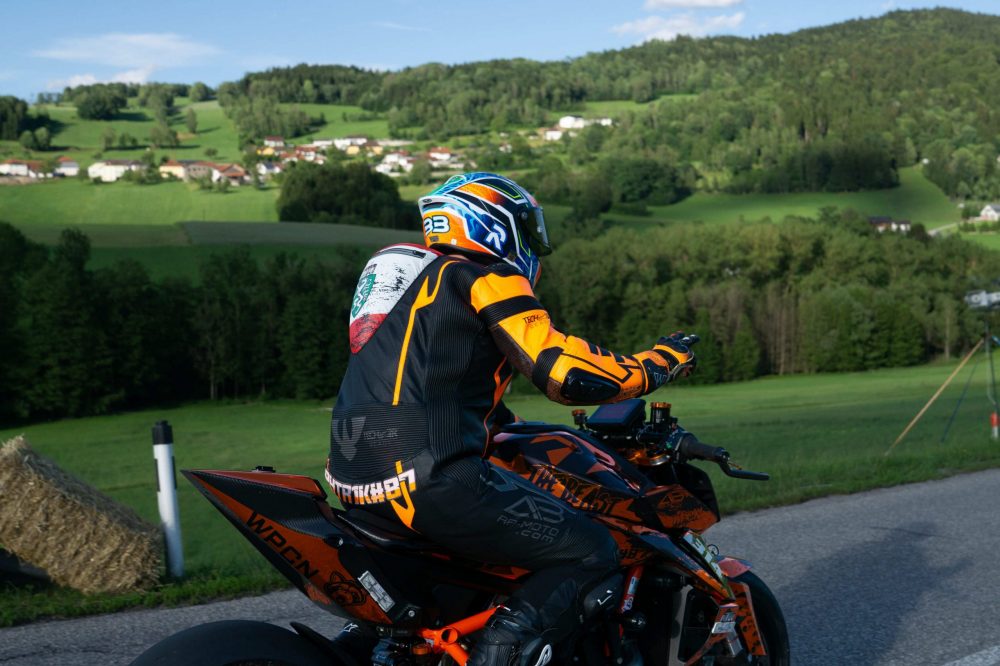 Bergrennen Julbach 2026 | Julbach, Oberösterreich Fahrer auf oranger KTM von hinten, im Hintergrund Hügel und Ort im Mühlviertel