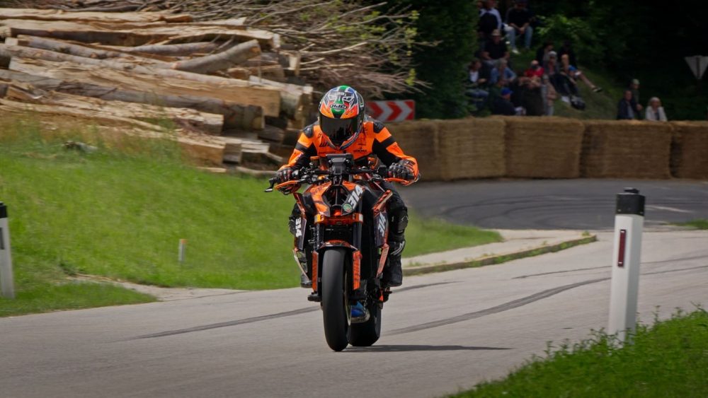 Bergrennen Julbach 2026 | Julbach, Oberösterreich KTM Super Duke mit Fahrer in oranger Kombi fährt an Holzstapeln vorbei aus der Kurve in Julbach