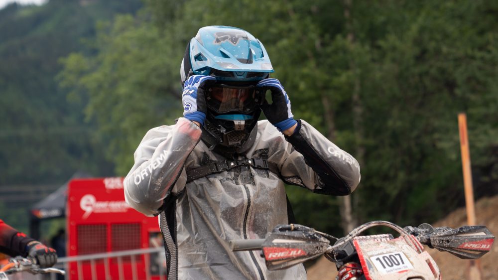 Endurofahrer mit hellblauem Helm richtet vor dem Start seine Brille