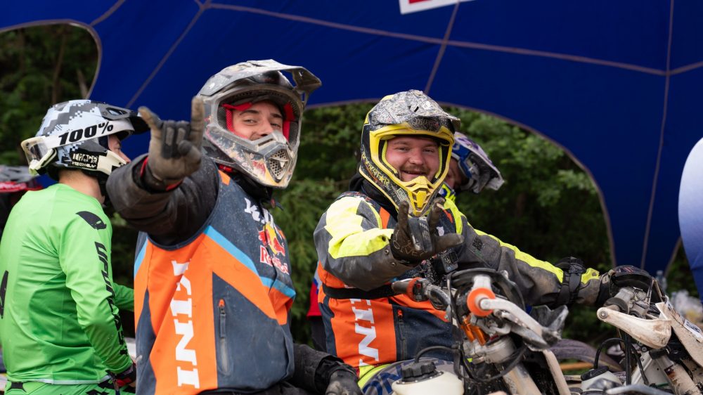 Mehrere Endurofahrer grüßen im Startbereich unter dem Red Bull Zelt