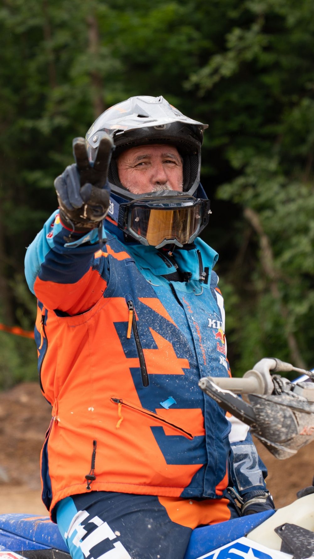 Endurofahrer in einer Jacke in Orange und Blau zeigt im Startbereich den Daumen nach oben