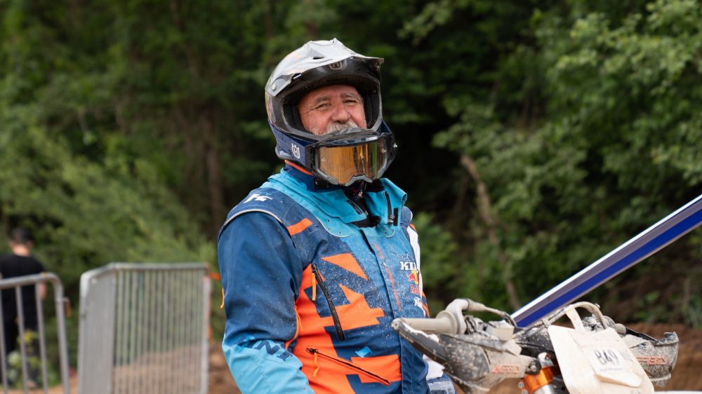 Lachender Endurofahrer am Erzberg, seine Ausrüstung in Blau und Orange