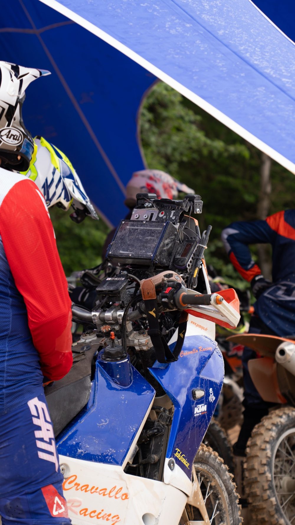 Fahrer mit blauer Enduro unter dem Red Bull Zelt im Startbereich