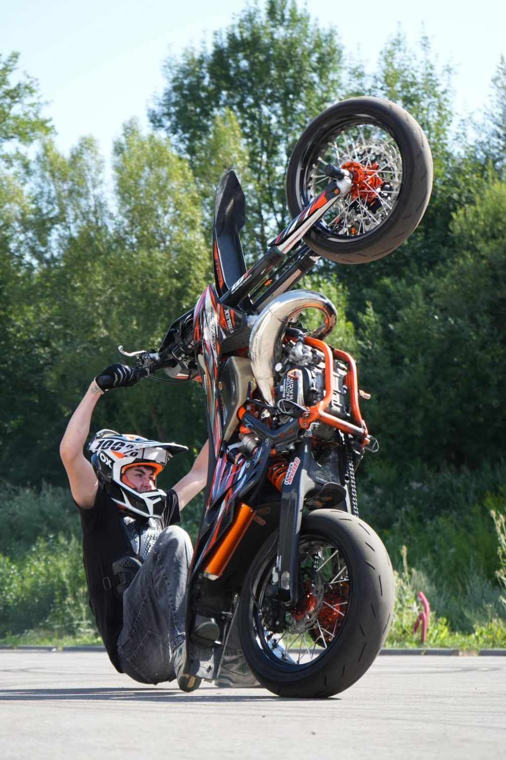 Stuntfahrer beim steilen Wheelie auf dem Gelände von AB-Moto