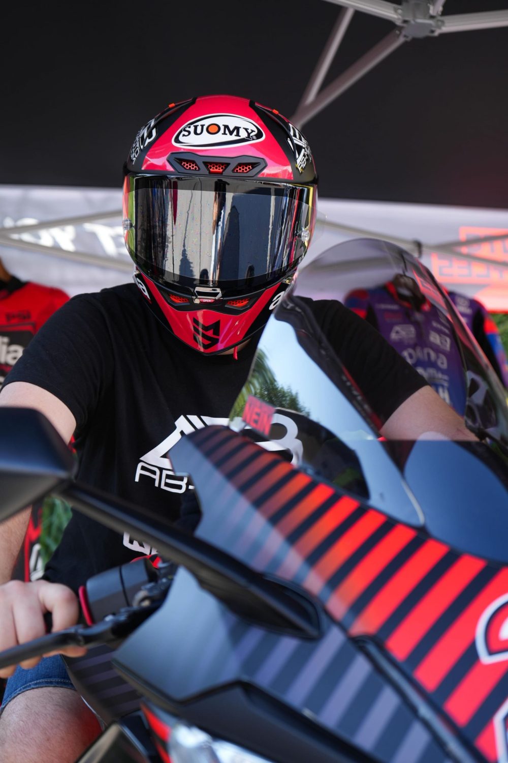 Besucher mit Helm auf dem MotoGP Simulator beim Sommerfest von AB-Moto