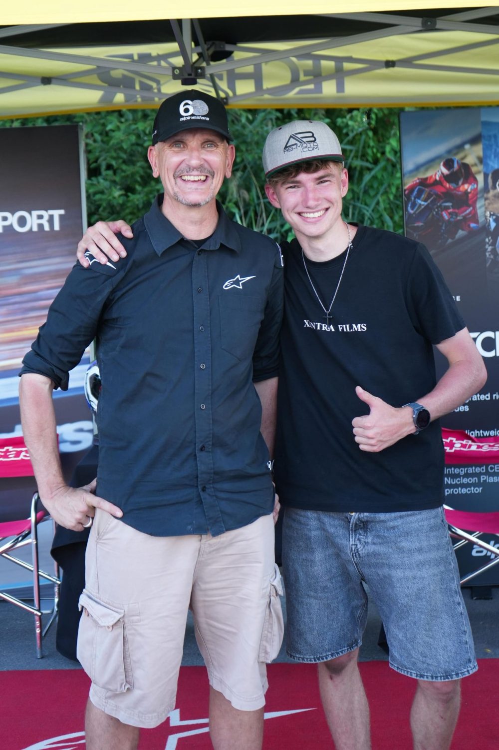 Zwei Männer in schwarzen Shirts posieren am Alpinestars Stand beim AB Moto Sommerfest