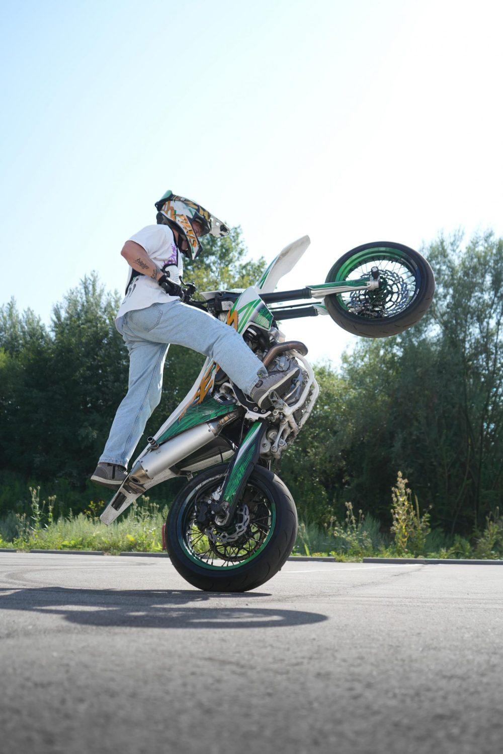 Stuntfahrer Pexis beim Wheelie mit ausgestrecktem Bein beim Sommerfest von AB-Moto