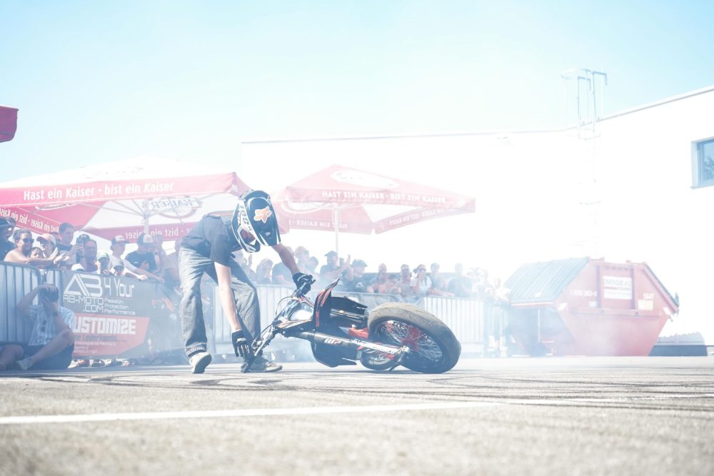 Stuntfahrer niklas.exc1 dreht im Reifenrauch vor Zuschauern beim AB Moto Sommerfest