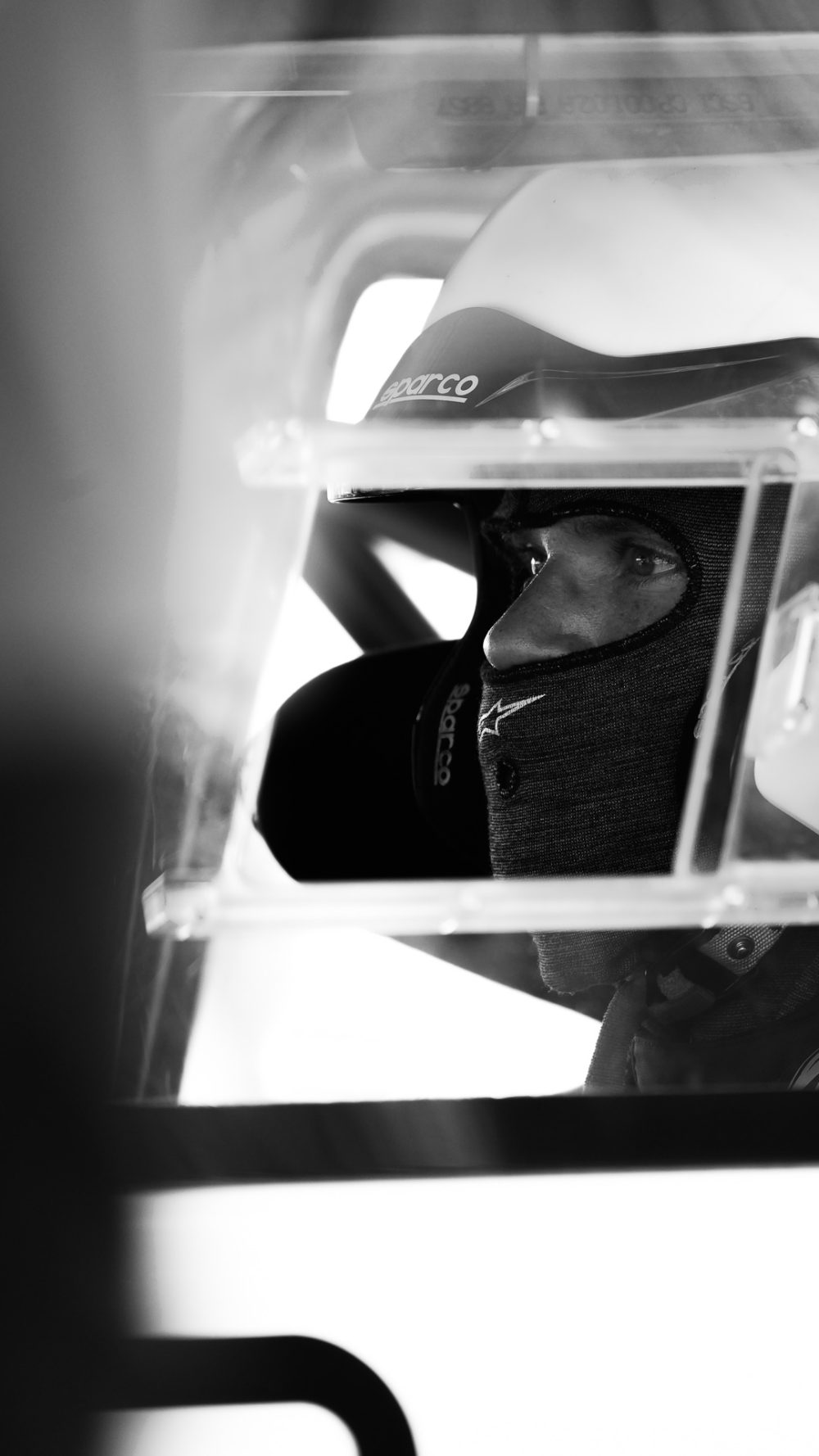 Bergrennen St. Agatha 2026 | Oberösterreich Schwarzweißes Portrait eines Fahrers mit Helm hinter dem Überrollkäfig im Cockpit