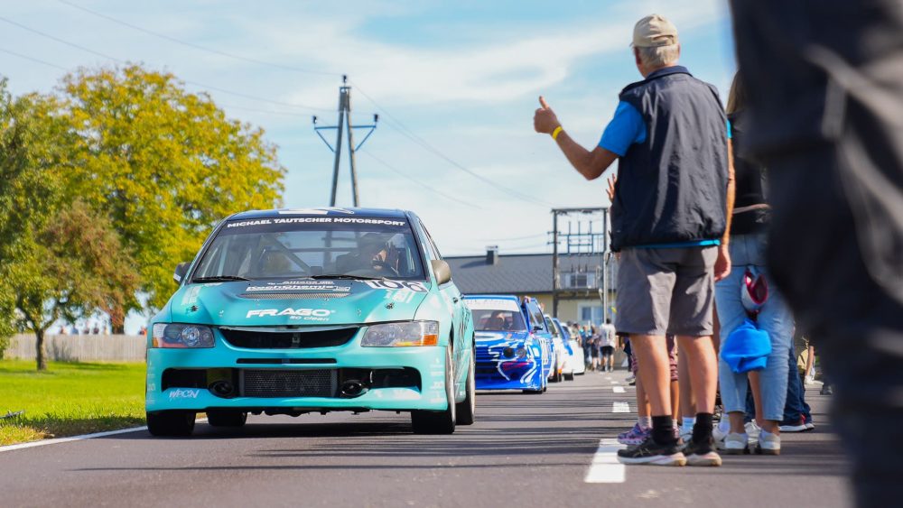 Daumen hoch vor dem Start Türkisfarbener Mitsubishi Lancer Evolution in der Startaufstellung, ein Offizieller zeigt den erhobenen Daumen