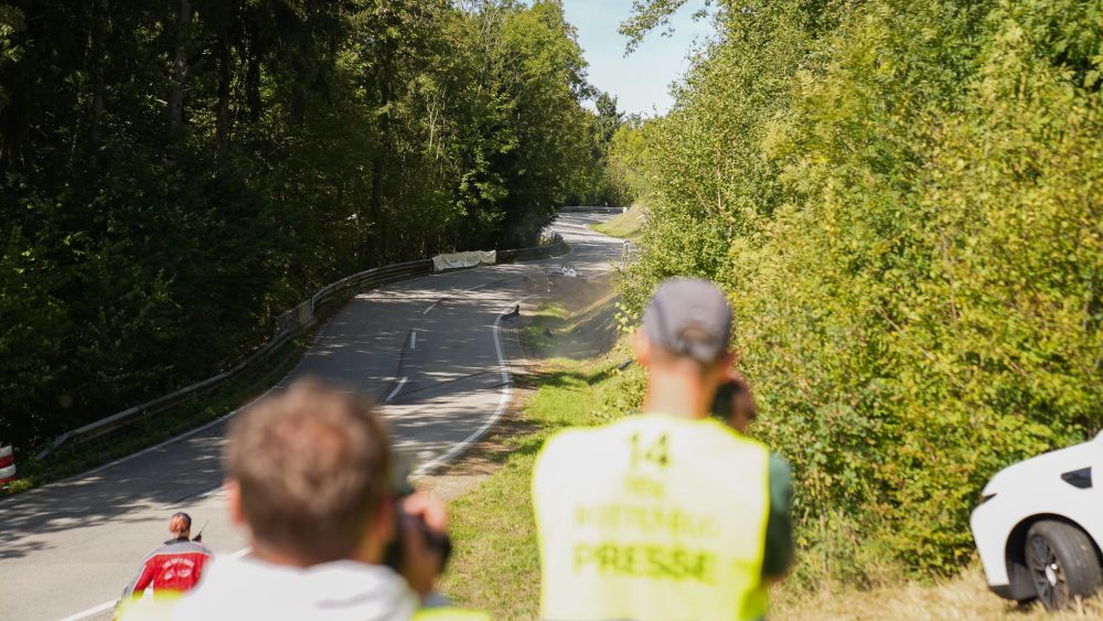 Presse an der Strecke Fotograf und Pressevertreter in gelber Weste am Streckenrand mit Blick auf die kurvige Waldstrecke