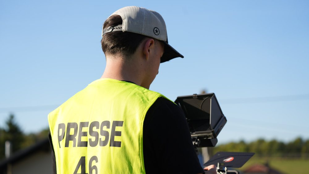 Konzentration am Monitor Nahaufnahme eines Kameramanns mit Kappe von hinten, der auf den Kameramonitor blickt, Weste mit Aufschrift PRESSE